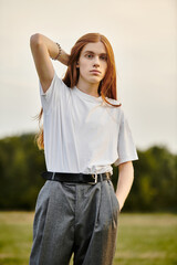 Young man with long hair showcasing modern fashion in a serene outdoor setting during sunset
