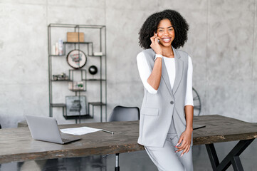 An African-American businesswoman has phone conversation, listens intently, a smile playing on her...
