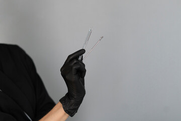 A cosmetologist dressed in black gloves holds various instruments designed for skin cleaning, ready...