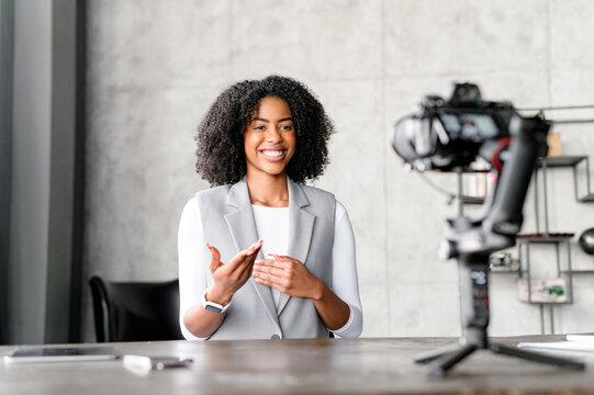 Businesswoman, teacher, mentor sitting in front of the camera, filming herself, passionately sharing insights or narrating a story, emphasizing her point in a captivating vlog or digital workshop