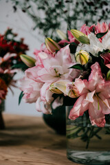 A vase of pink flowers sits on a wooden table. The flowers are arranged in a way that creates a sense of harmony and balance. The table itself is made of wood, which adds a natural