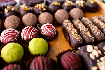 Assorted gourmet chocolate truffles and bars with nut toppings on wooden table