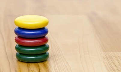 Stack of colorful wooden toy circles on a wooden floor, balanced, ready to play, and learn basic color recognition and coordination