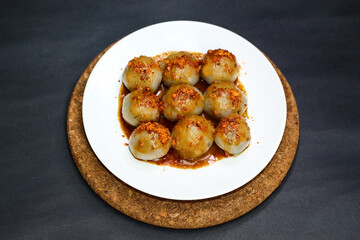 Cilok, served in white plate with peanut sauce. Popular snack from Indonesia made by tapioca flour. isolated black background. Selective focus.