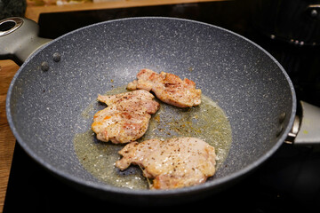 Chicken frying in a frying pan on a cooker