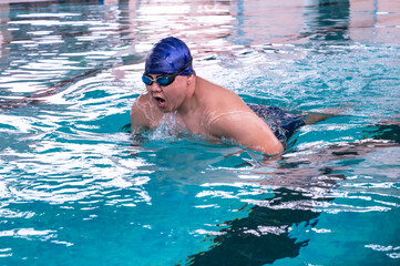 Fat Asian male swimmer swimming breast stroke action in pool