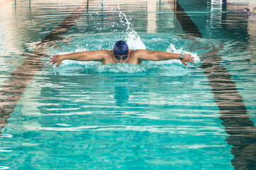 Fat Asian male swimmer swimming butterfly in pool