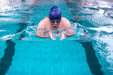 Fat Asian male swimmer swimming breast stroke action in pool