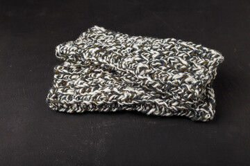 Melange white grey wool yarn knit mittens on black background. Knitted clothes, accessories. Knitting as leisure activity