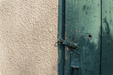 An old green door with an old hook and a barn wall.