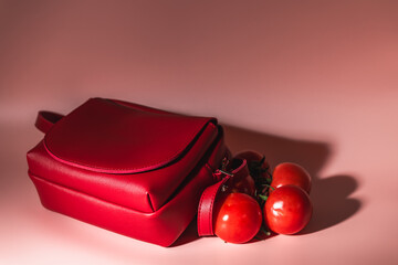 Abstract photo of red bag and tomatoes on pink background. Red like tomato.