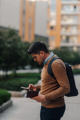 Fototapeta premium Businessman using smartphone and holding wallet in urban setting