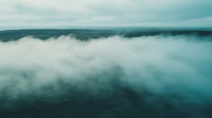 Obraz premium Aerial view of mist covering vast landscape under cloudy skies