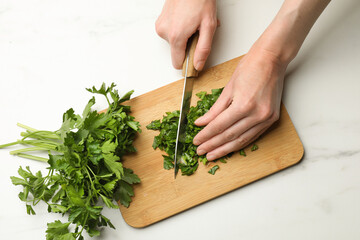 Woman cutting fresh parsley at white table, top view