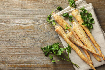 Raw parsley roots with leaves on wooden table, top view. Space for text