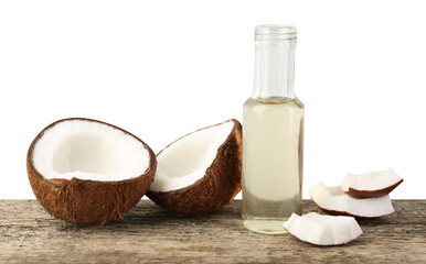 Organic coconut cooking oil in glass bottle and pieces of fresh fruit on wooden table against white background