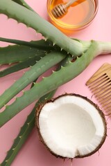 Hair treatment. Fresh coconut, honey, comb and aloe leaves on pink background, flat lay