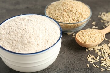 Brown rice and flour on grey table, closeup