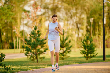 Sporty woman enjoys a refreshing jog in a vibrant park surrounded by nature