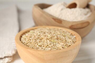 Brown rice and flour on white wooden table, closeup