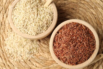 Different sorts of raw brown rice on wicker mat, top view