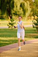 Sporty woman enjoys a refreshing run through the park under the golden sun during afternoon