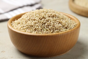Brown rice in bowl on light grey table, closeup