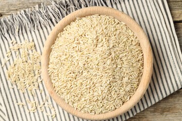 Brown rice in bowl on wooden table, top view