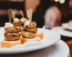 Mushroom-topped crostini tapas on a white plate in a moody restaurant