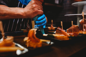 Chef piping savory cream onto tapas in a professional kitchen