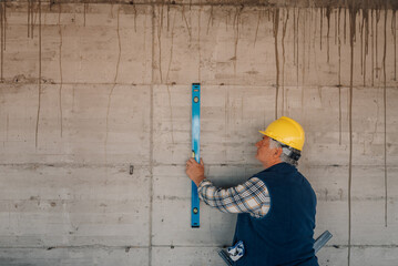 Construction worker using spirit level on concrete wall
