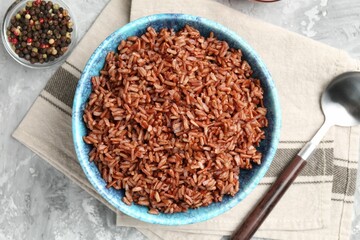 Delicious brown rice served on grey textured table, flat lay