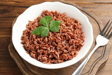 Delicious brown rice with parsley served on wooden table, closeup