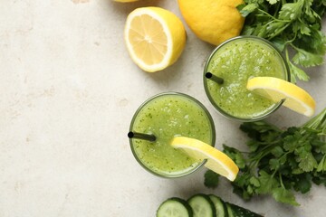 Healthy parsley smoothie in glasses, leaves, lemon and cucumber on light textured table, flat lay....
