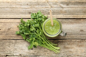 Healthy parsley smoothie in mason jar and leaves on wooden table, flat lay