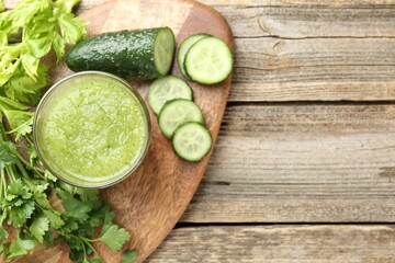 Healthy parsley smoothie in glass, leaves, cucumber and celery on wooden table, top view. Space for...