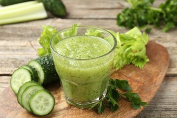 Healthy parsley smoothie in glass, leaves, celery and cucumber on wooden table, closeup