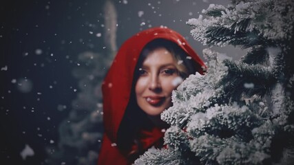 Portrait happy woman hiding behind tree, looking around in dark night forest winter nature snow falling fog, fairy tale Fantasy girl princess beauty face lips eyes red hood on head cape white dress - Powered by Adobe