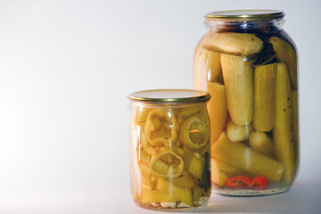 Vegetable marinade on white background. Canned sour vegetables in glass jars. Pickled vegetables in a jar - cucumbers, tomatoes, peppers, okra.