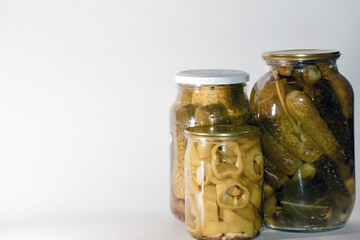 Vegetable marinade on white background. Canned sour vegetables in glass jars. Pickled vegetables in a jar - cucumbers, tomatoes, peppers, okra.