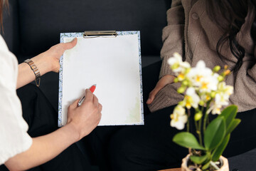 Young woman holding folder and taking notes close-up