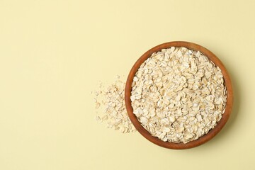 Composition with oatmeal flakes on beige background. Cooking breakfast