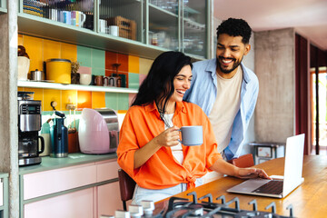 Couple enjoying coffee while working together in a cozy colorful kitchen
