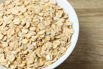 Composition with oatmeal flakes on wooden background. Cooking breakfast