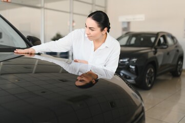 Young woman choosing a car at car showroom