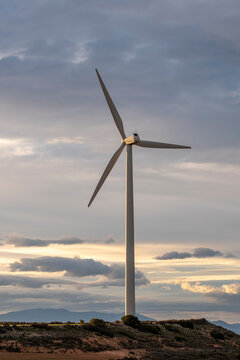 Wind turbine against a textured sky at dusk, showcasing the contrast between nature and sustainable technology in Zaragoza&rsquo;s evolving energy landscape.