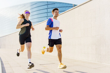 Two runners enjoy a sunny morning workout on a modern urban pathway near a sleek building