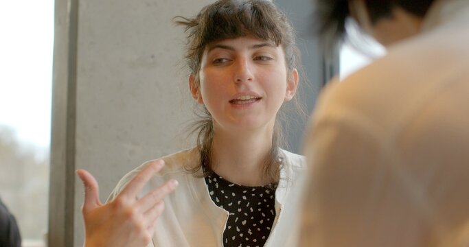 A woman engages in conversation at a cafe. Focused presence reflect leadership and expertise in a dynamic business setting. Human hand gesturing