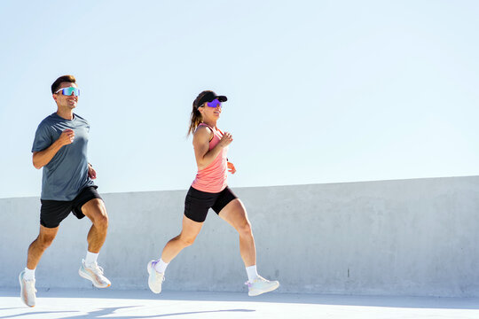 Runners enjoy a sunny day exercising on a rooftop track in a modern urban setting