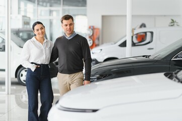 Portrait of a beautiful young couple choosing a new car at a car dealership